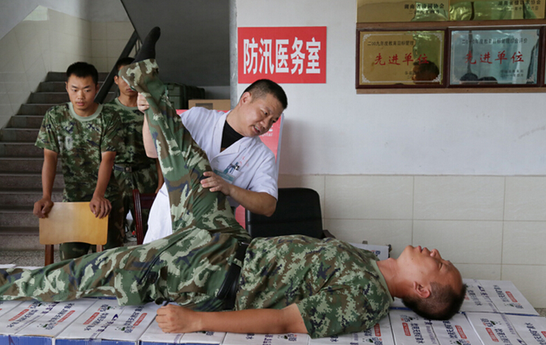 圖為醫(yī)療隊醫(yī)生在為8730部隊武警抗洪部隊官兵進行中醫(yī)正骨治療。